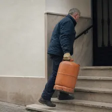 Repartidor subiendo una bombona de gas por la escalera de un portal