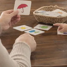 Logopeda trabajando con tarjetas de imágenes en la mesa del domicilio de un paciente